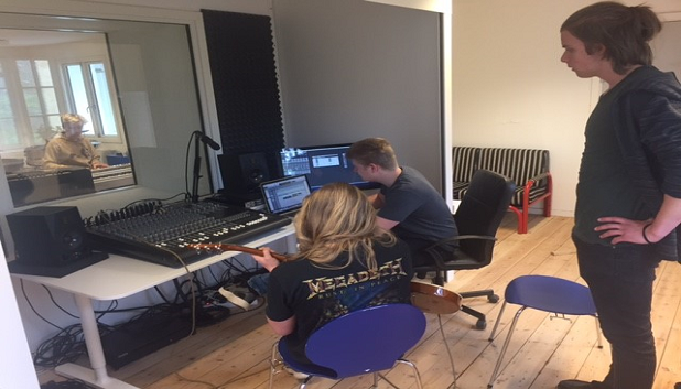 Musiklaboratoriet 1. Tre unge i et øvelokale med mixerpult og et par skærme.