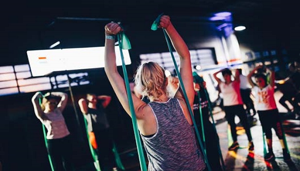 fitness fo alle. Instruktør viser øvelser med elastik for en gruppe unge