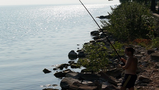 Go Fishing fls. En person står og fisker med stand ved havet